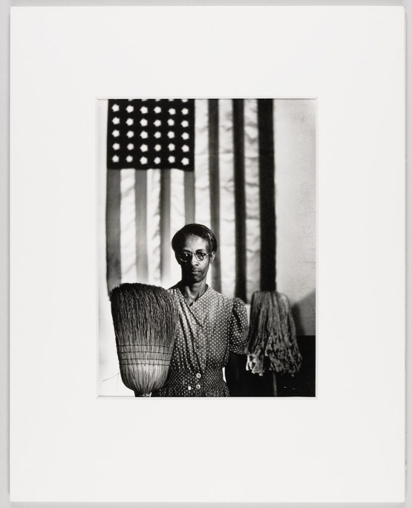 femme noire posant avec un balai devant le drapeau américain