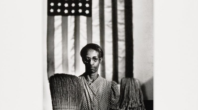 femme noire posant avec un balai devant le drapeau américain